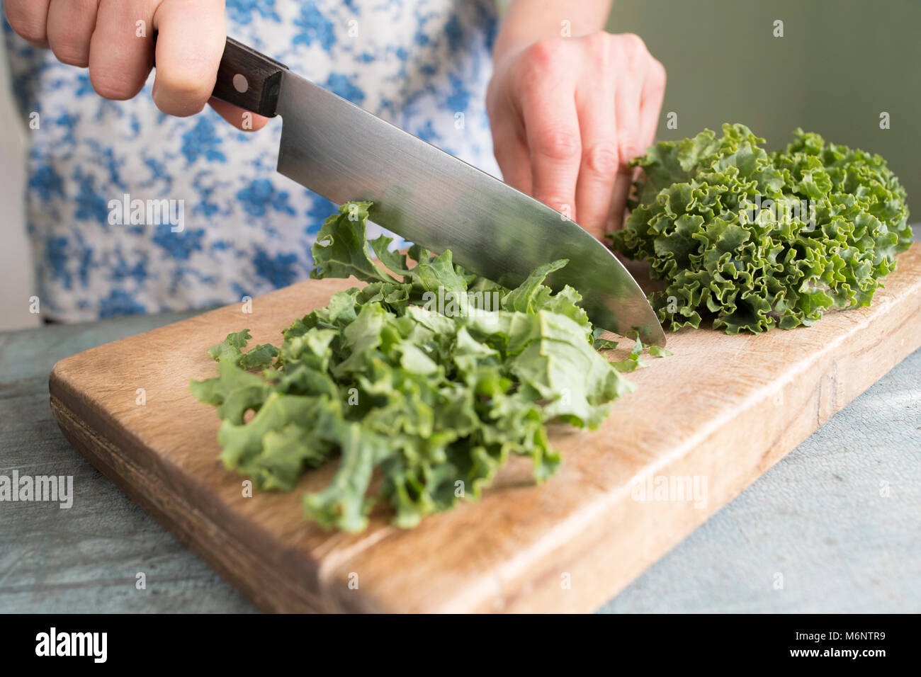 Close up della donna la preparazione di Kale sul tagliere Foto Stock