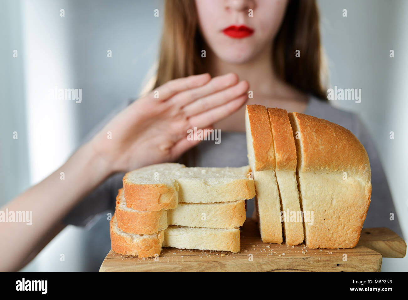 Intolleranza al glutine e concetto di dieta. Giovane ragazza si rifiuta di mangiare il pane bianco. Profondità di campo. Messa a fuoco selettiva su pane Foto Stock