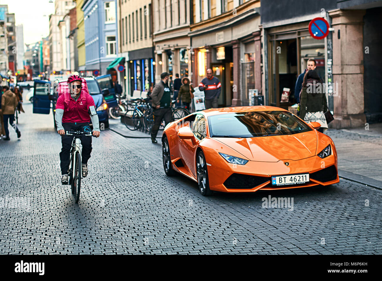 Orange Lamborghini Huracan LP 580-2 Spyder auto rilasciato circa 2016 in Italia parcheggiato sulla strada con una bicicletta courier passando da. Foto Stock