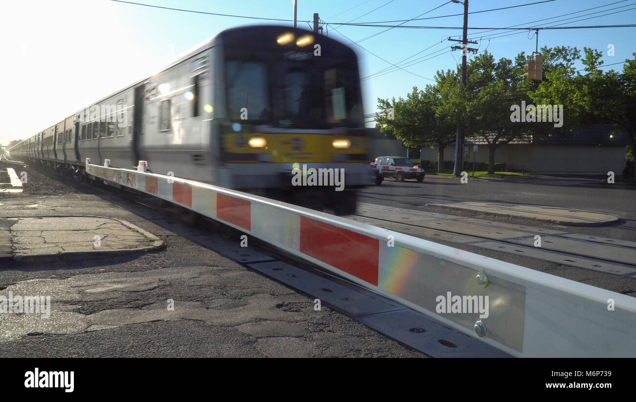 Long Island, NY - Circa 2017: Ferrovia di Long Island treno attraversando porta di sicurezza xing alla stazione locale. La sfocatura in movimento ad alta velocità di transito pubblico pendolari. Mo Foto Stock