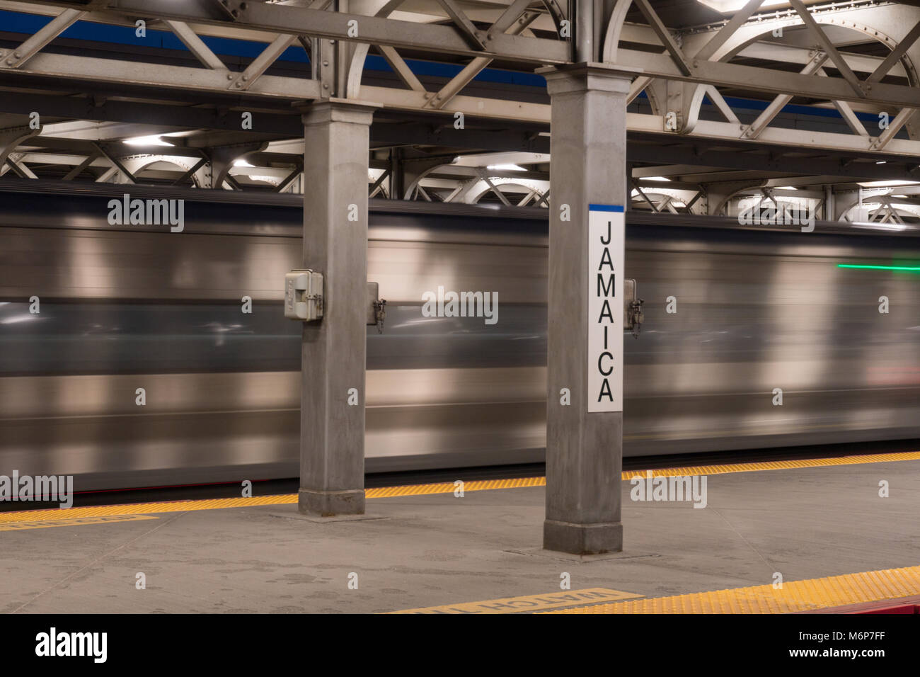 La città di New York, circa 2017: LIRR Long Island Railroad express train lunga esposizione motion blur che viaggiano attraverso la Giamaica terminal della stazione di segno della piattaforma Foto Stock