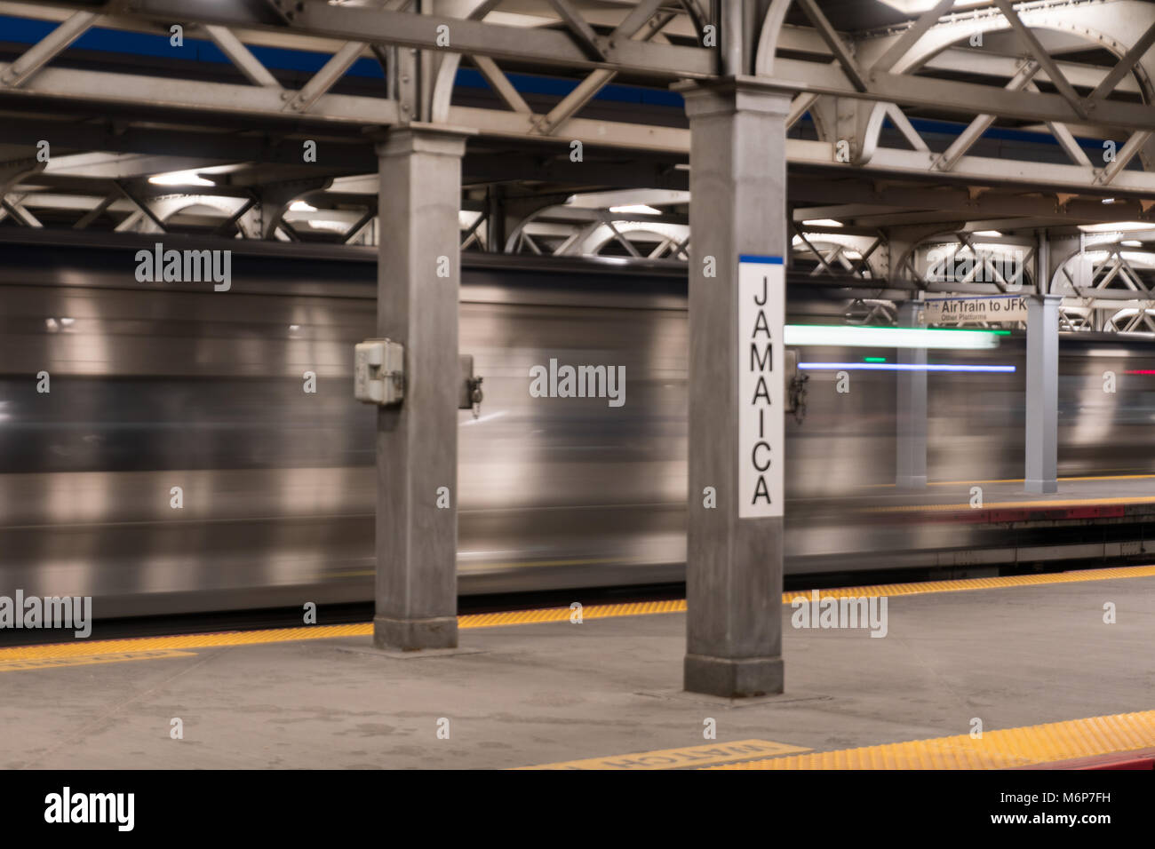 Long Island, NY - Circa 2017: lunga esposizione Giamaica railroad station terminal platform express treno passa attraverso occupato il trasferimento di massa hub di transito Foto Stock