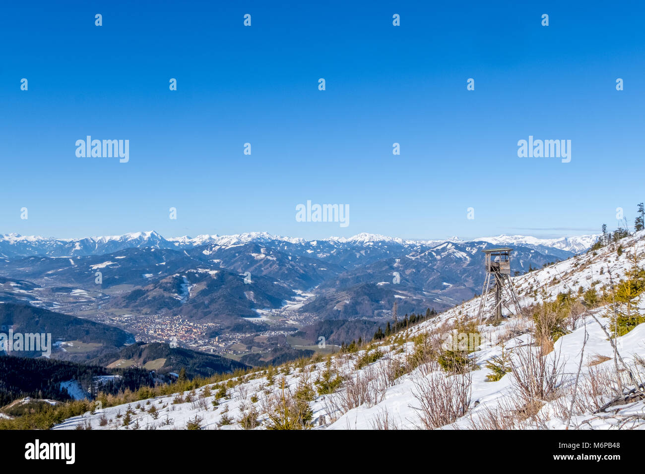 Torre di avvistamento sulla montagna innevata Rennfeld vista sulla vallata Muerztal con città di Bruck an der Mur a montagne Goesseck, Stadelstein, Eisenerzer Reichenste Foto Stock