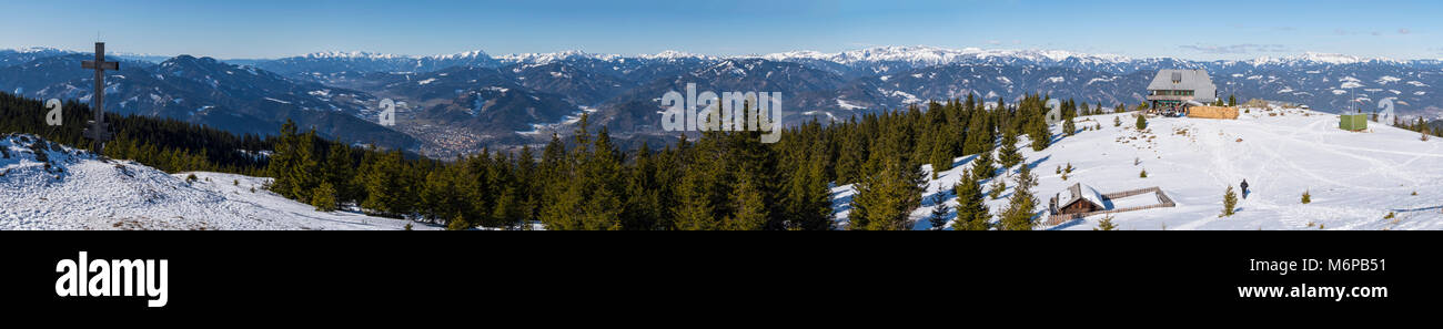 Ampio paesaggio panoramico del vertice di croce e rifugio sulla cima dalla montagna Rennfeld e lontane cime delle montagne in inverno Foto Stock