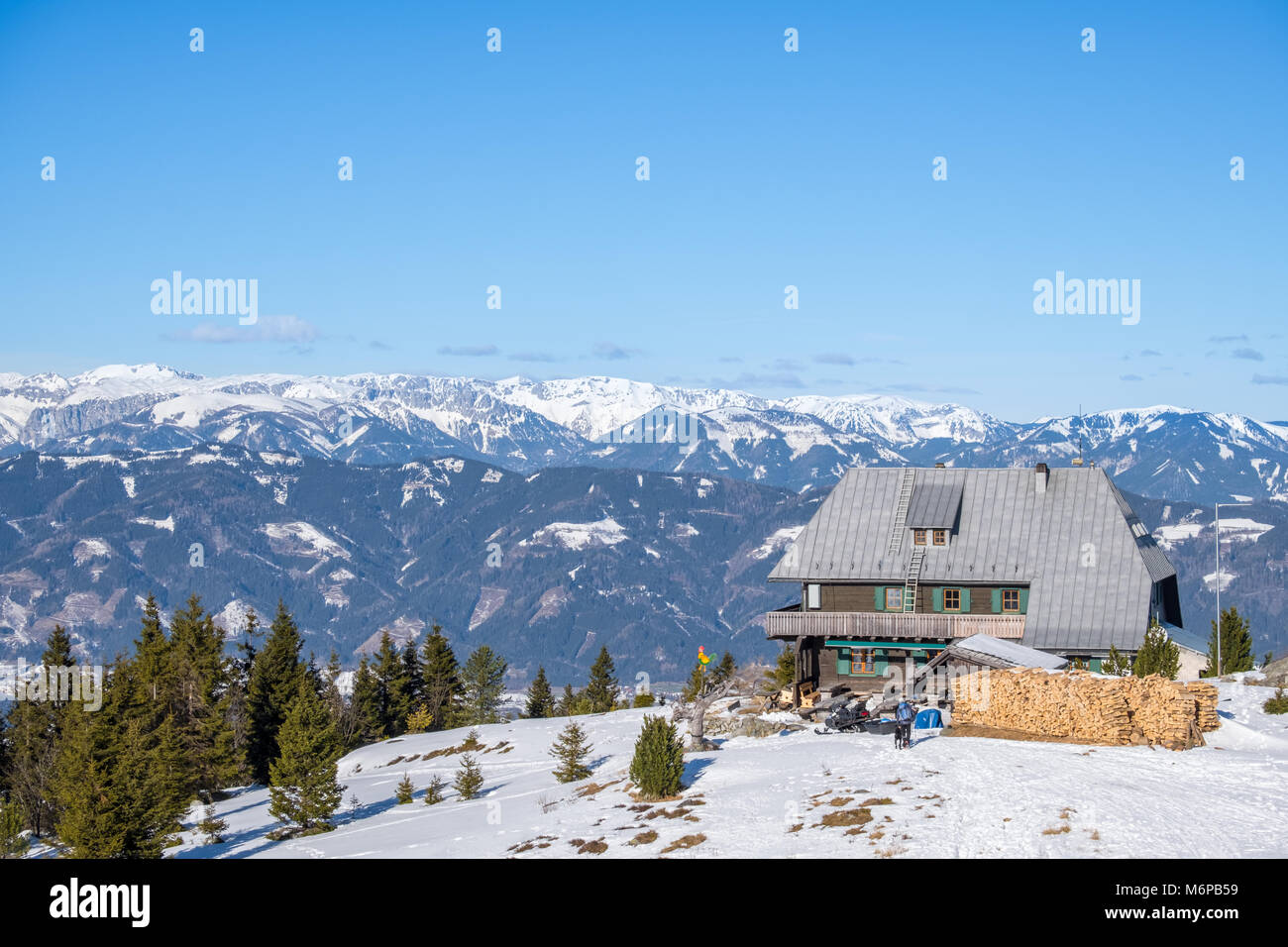 Vista della capanna dal vertice nevoso di montagna Rennfeld e lontane cime della catena montuosa Hochschwab in inverno Foto Stock