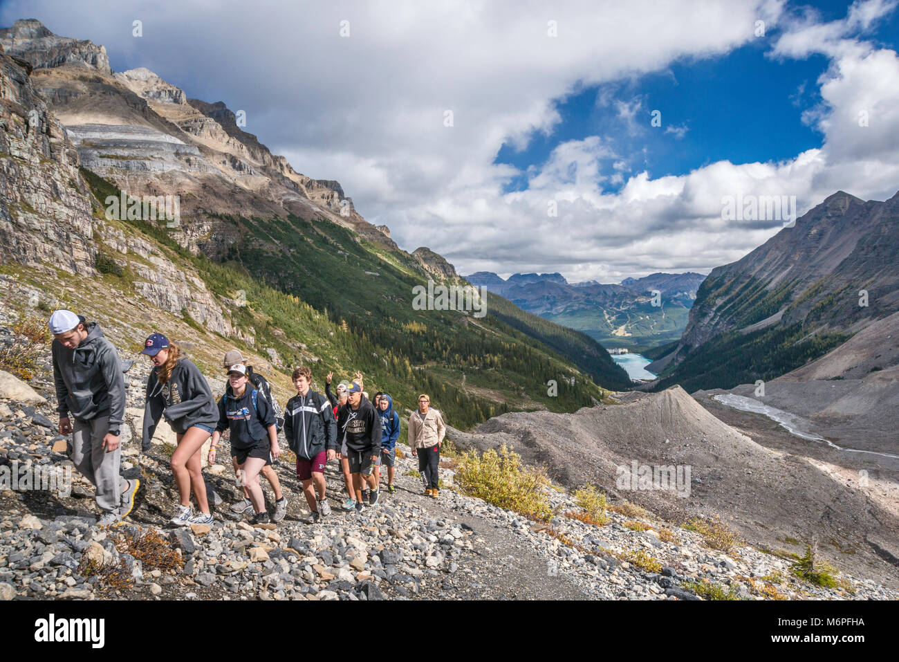 Gruppo di studenti sulla pianura del sei ghiacciai sentiero inferiore su Ghiacciaio Victoria, il Lago Louise in distanza, il Parco Nazionale di Banff, Alberta, Canada Foto Stock