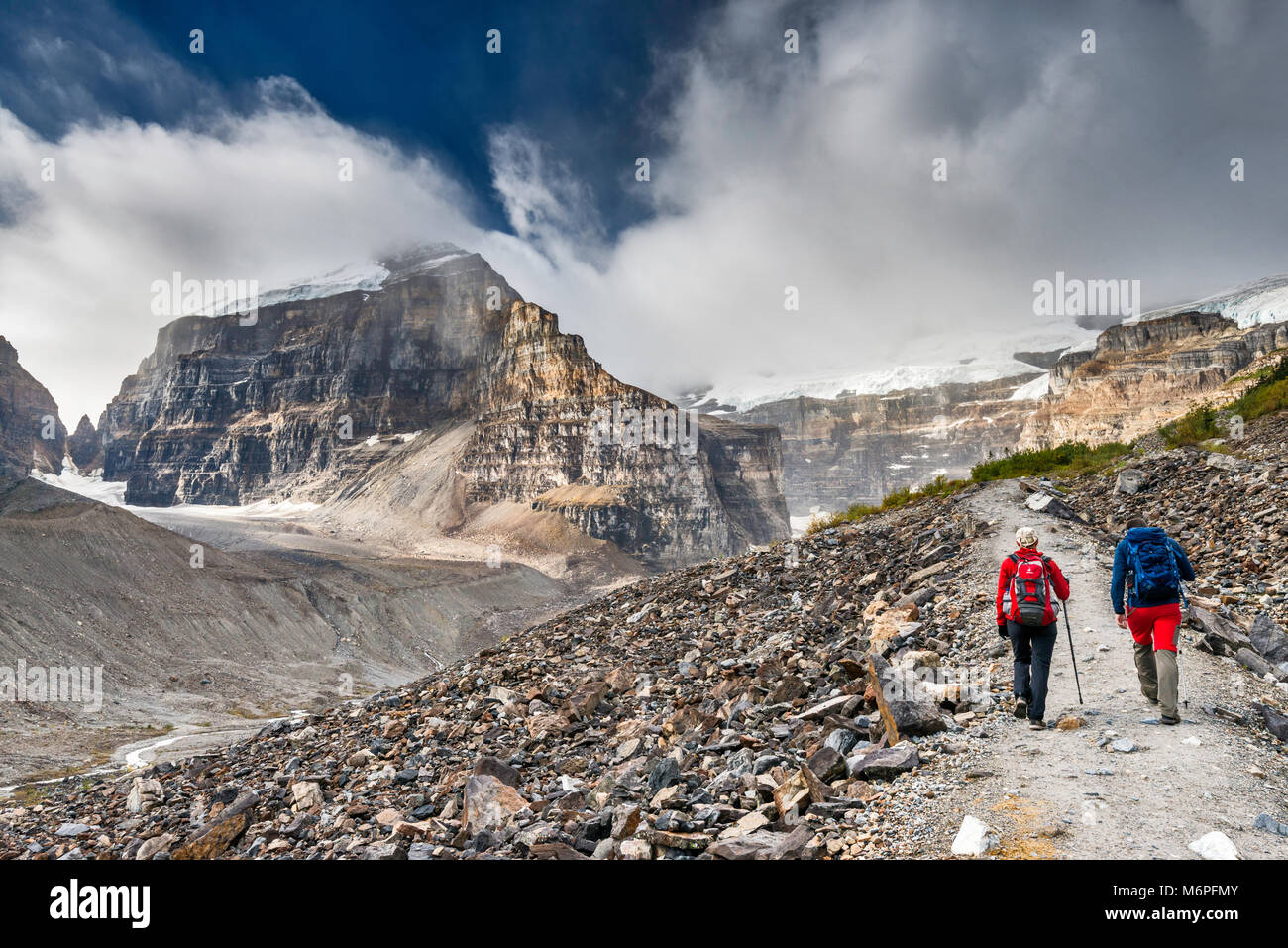 Gli escursionisti sulla pianura del sei ghiacciai Trail, scree-pendenze coperte, Monte Lefroy sulla sinistra, il Monte Victoria in nuvole, il Parco Nazionale di Banff, Alberta, Canada Foto Stock