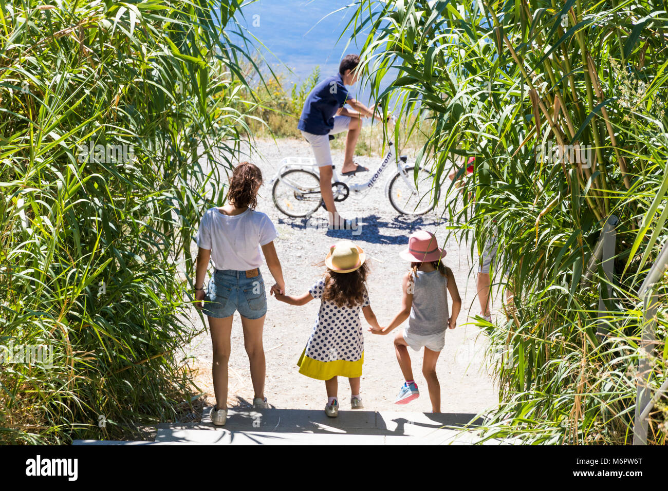 Giovani caucasici felice famiglia di tre bambini all'aperto la bici e camminare nei pressi di un lago in Maguelone, Francia Foto Stock