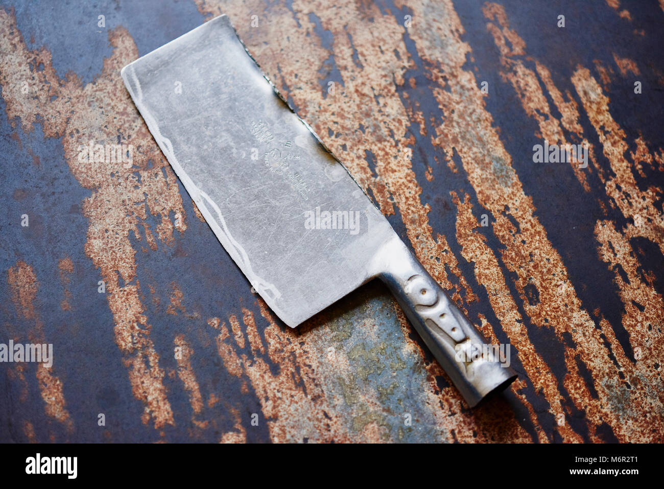 Grande la cucina dello chef coltello cleaver vintage in distressed la superficie del tavolo Foto Stock