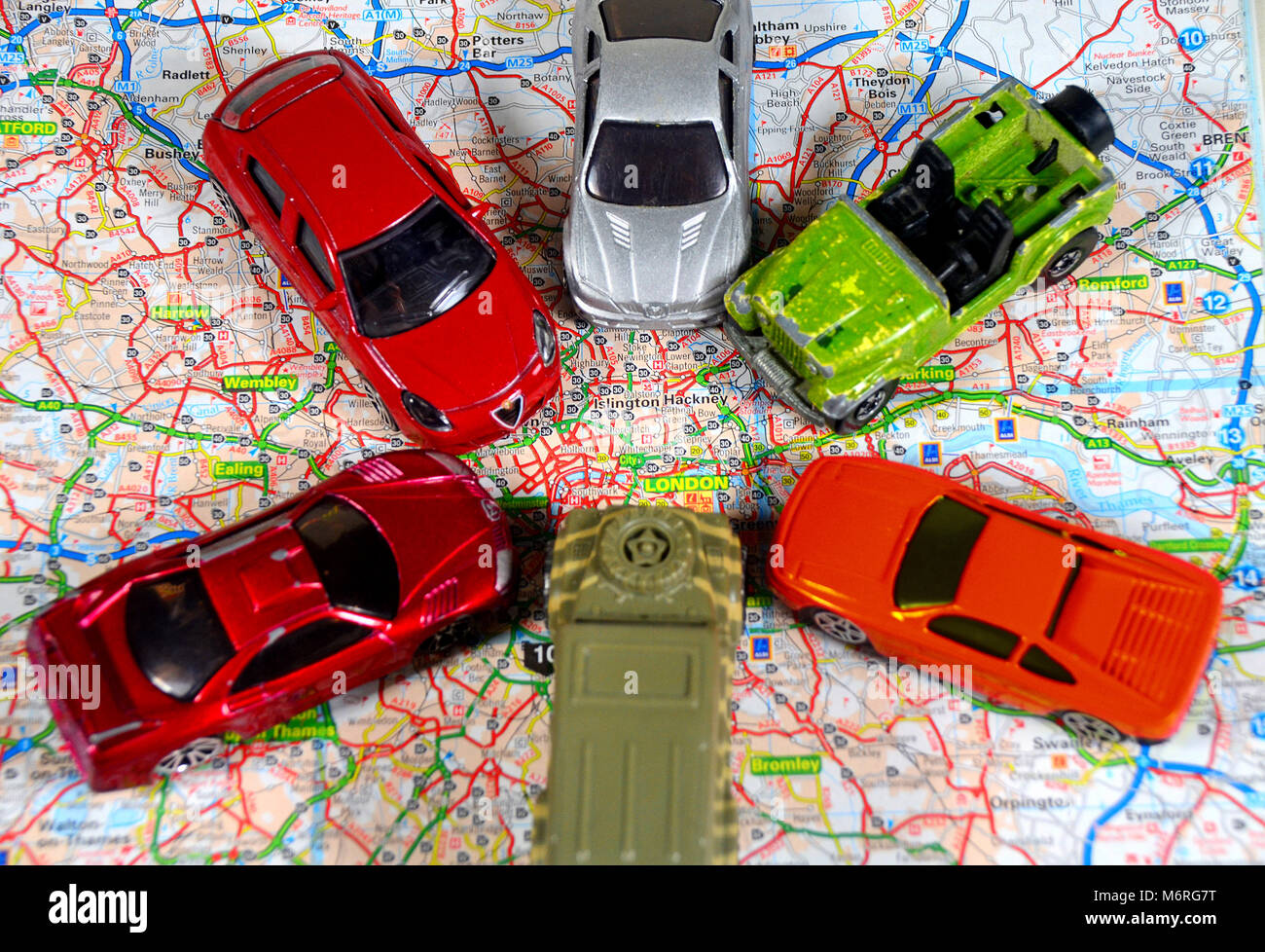 Concetto di traffico che entra Londra da tutte le direzioni - utilizzo di automobili giocattolo e una mappa stradale della Gran Bretagna. Foto Stock