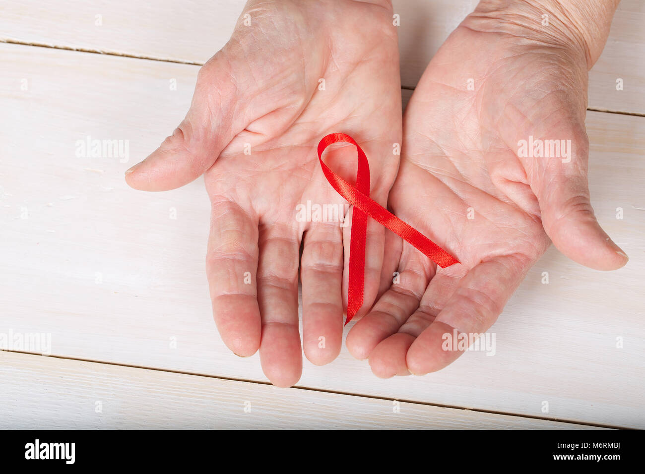 Vecchia donna mostra di seta rossa ribbon.Closeup Foto Stock