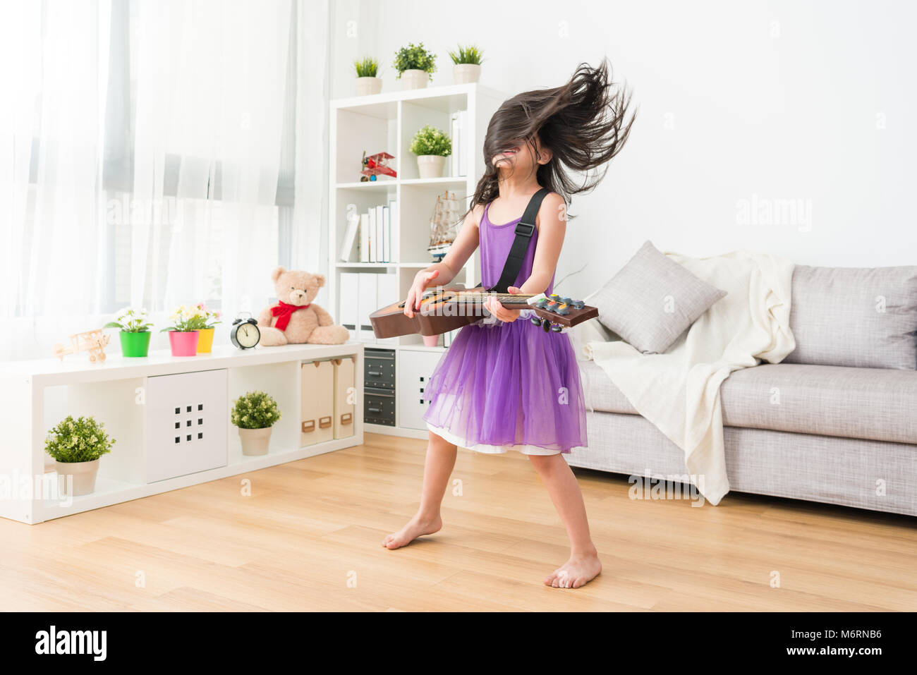Asian babe ragazza suonare la chitarra in un proprio stile. Ella gode di se stessa in prestazioni di stile rock musica. Foto Stock