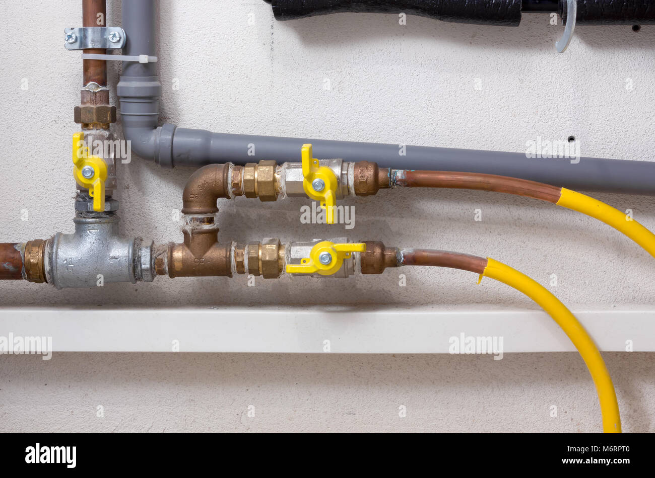 Rame e plastica Tubazioni e valvole di giallo in un locale caldaia Foto Stock