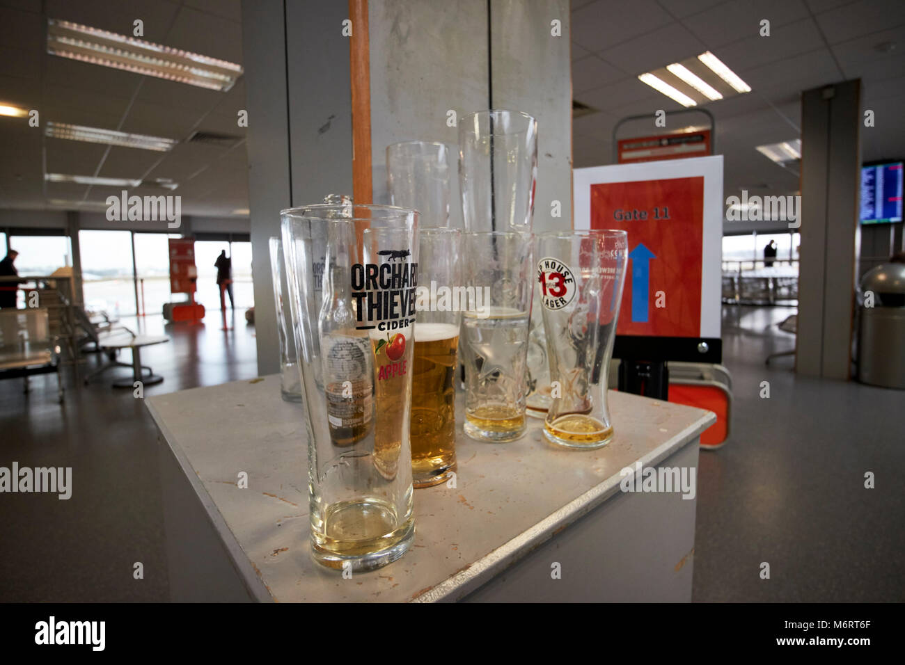Vuoto e mezzo finito pinte di alcol rimanente in un aeroporto partenza lounge prima di salire in aereo nel Regno Unito Foto Stock