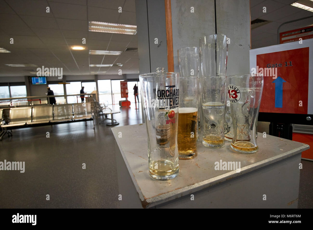 Vuoto e mezzo finito pinte di alcol rimanente in un aeroporto partenza lounge prima di salire in aereo nel Regno Unito Foto Stock