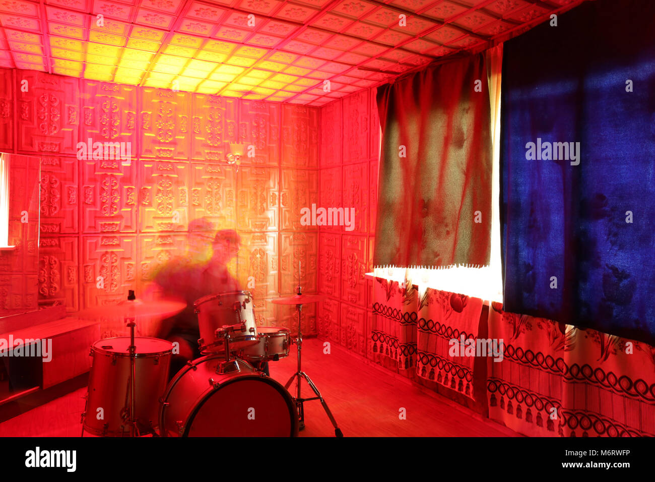 La musica, la passione, il concetto di creazione. nella stanza isolata che è illuminato da luminose sanguinosa luce rossa si è offuscata la figura del musicista maschio la riproduzione Foto Stock