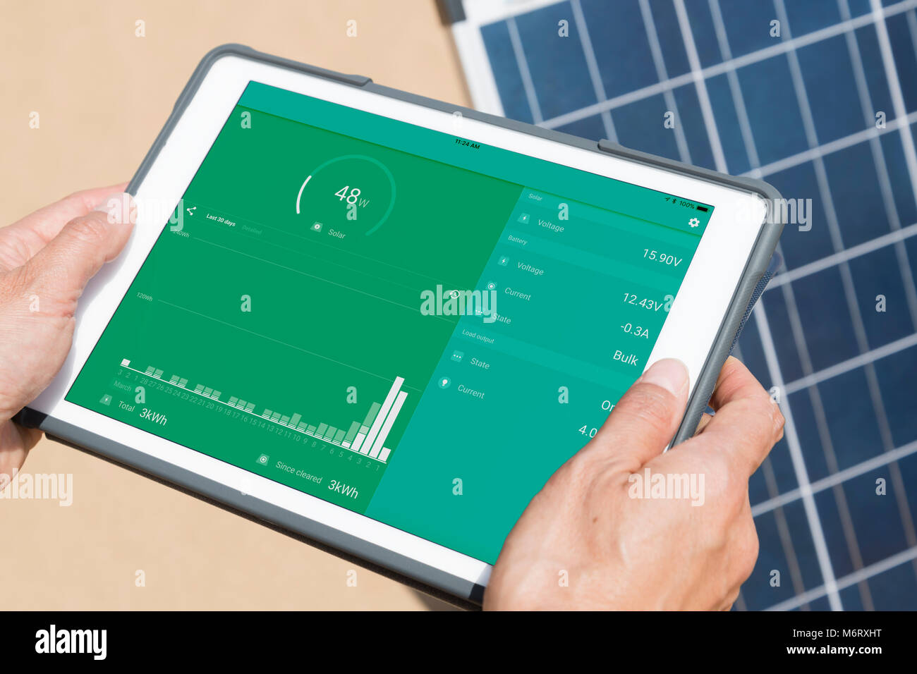 La donna le mani sulla tavoletta elettronica controllando il suo pannello solare (schermo verde con le statistiche e il grafico della produzione di energia e consumo) Foto Stock