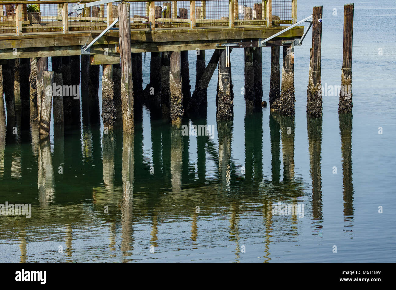 Pontili in legno vengono riflesse in acqua calma vicino a un dock Foto Stock