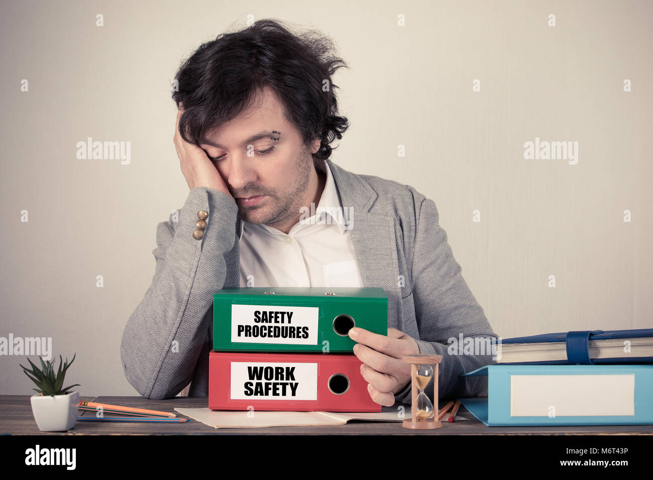 Sicurezza del lavoro e le procedure di sicurezza il testo sui leganti, preoccupati pensando bussinesman dalla scrivania Foto Stock