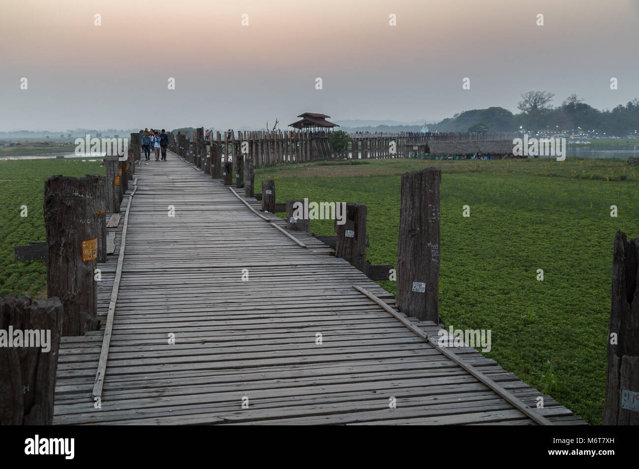 Alcune persone all'U Bein Bridge ad Amarapura vicino a Mandalay in Myanmar (Birmania) al tramonto. È il più antico e il più lungo ponte in teak nel mondo. Foto Stock