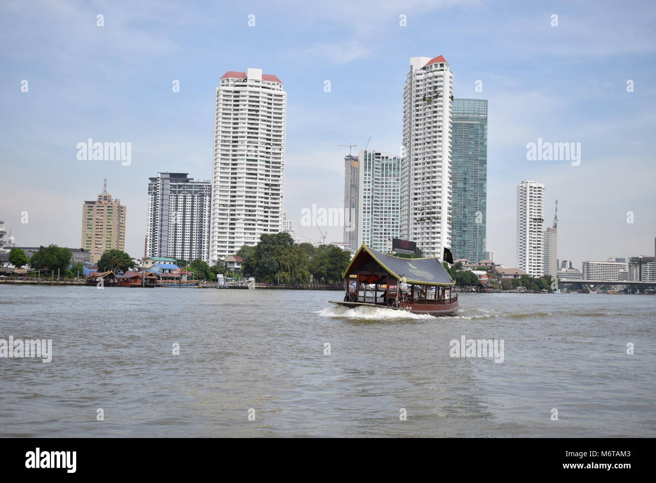 Hotel battello navetta nel mezzo del fiume Chao Phraya in Bangkok con Skyscrappers e cielo blu in background. Foto Stock