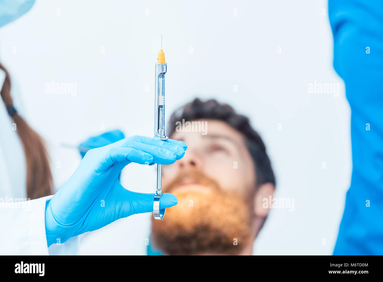 Close-up della mano di una femmina di dentista indossando sterile guanto chirurgico tenendo un anestetico dentale siringa prima di trattare un paziente Foto Stock