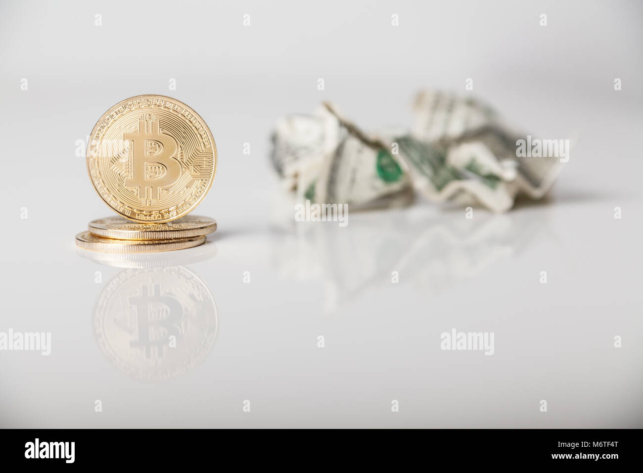 Crypto valuta. Oro monete bitcoin e accartocciata dollari su sfondo bianco Foto Stock