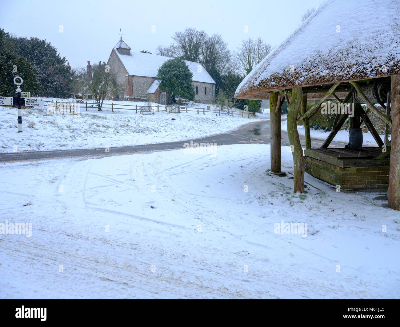 Neve invernale scena, la chiesa di San Pietro e il borgo ben con il tetto di paglia, Est Marden, West Sussex, Regno Unito Foto Stock