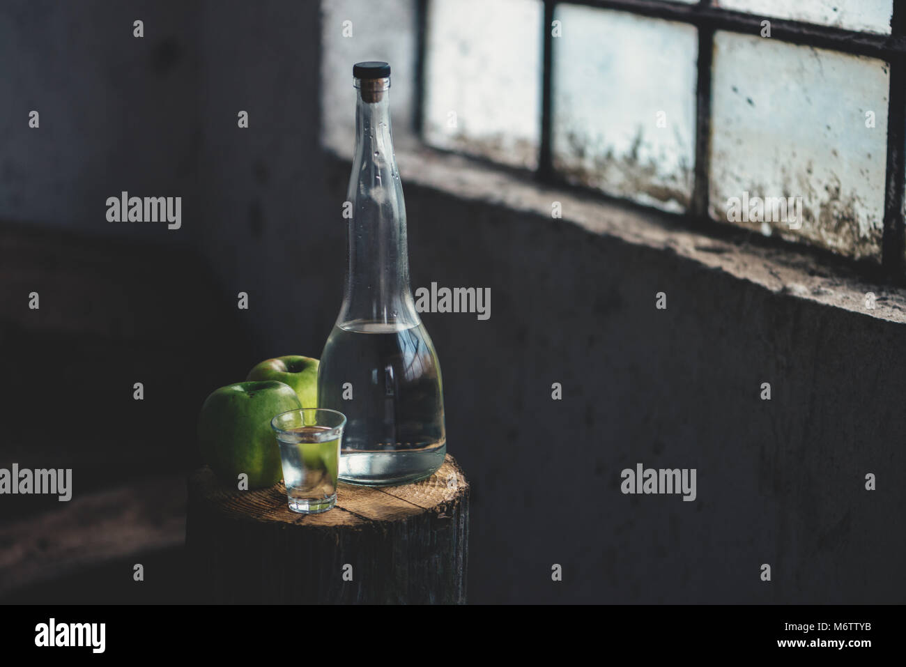 Apple brandy, rustica atmosfera rétro. Bottiglia e unico colpo di vetro con alcool bere e due verde mela frutta. Foto Stock