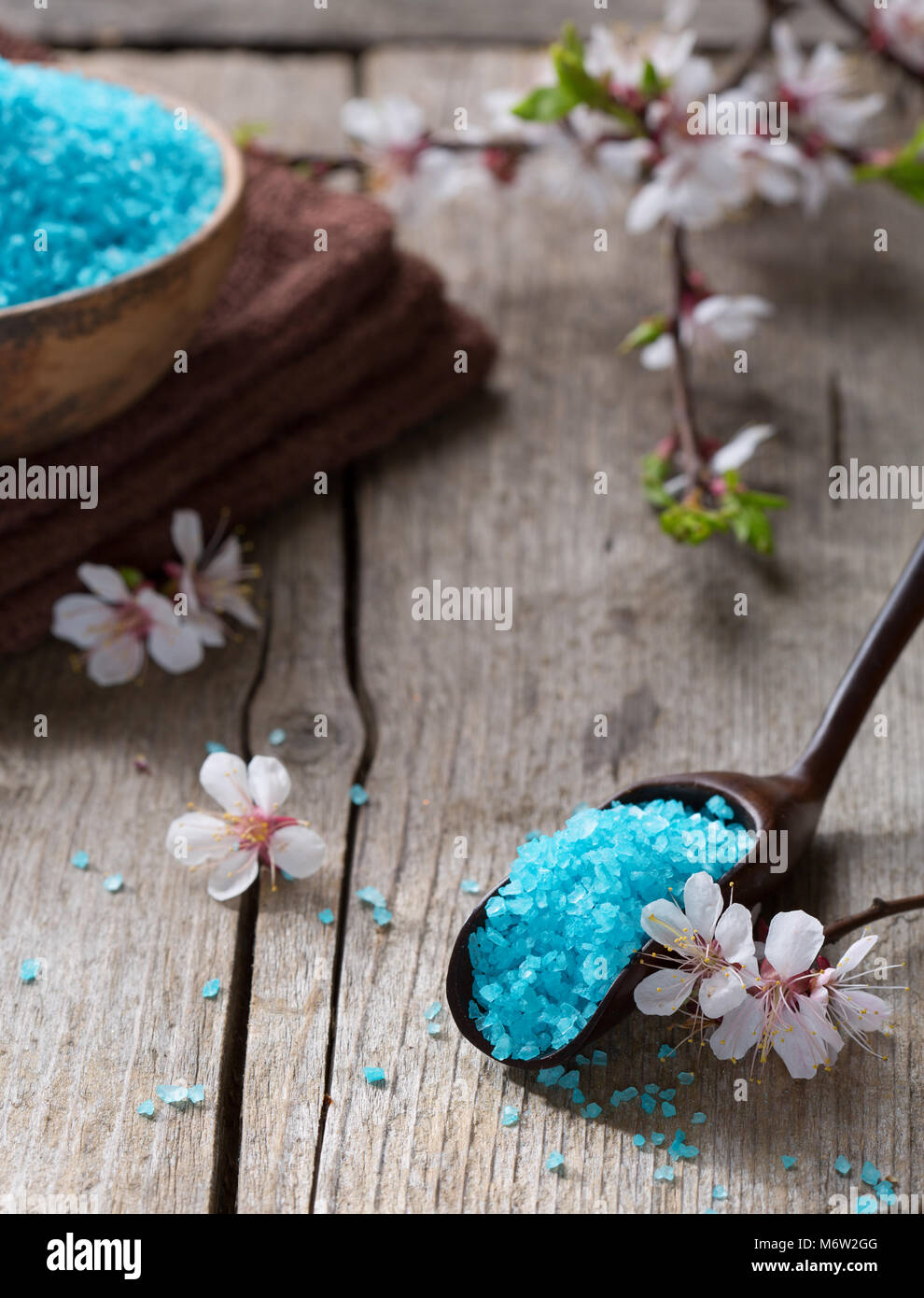 Minerali di sali da bagno, asciugamani e fiori sul vecchio tavolo in legno. Dof poco profondo Foto Stock