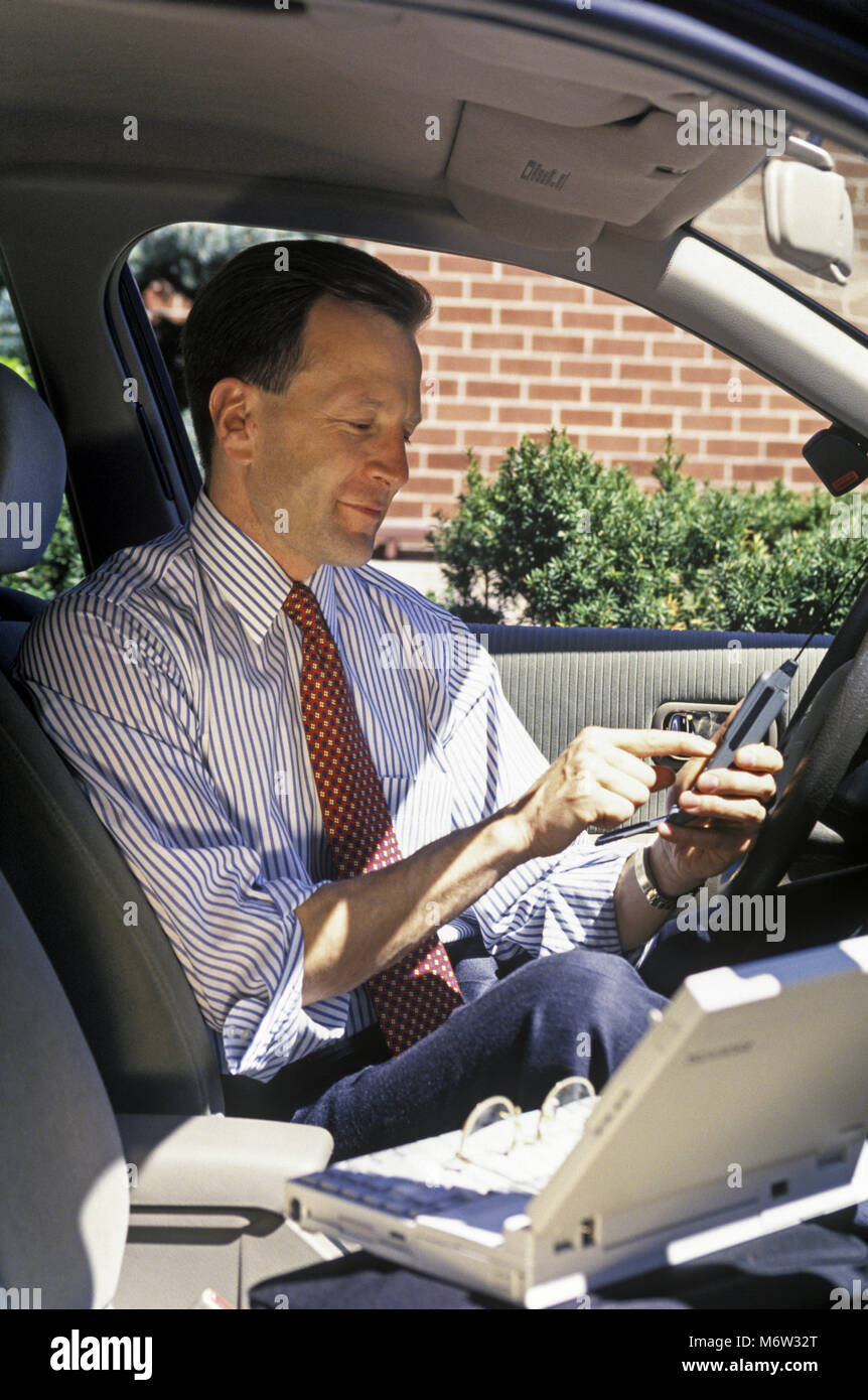 1995 caucasico storico vendite business man con telefono cellulare (©MOTOROLA CORP 1995) IN AUTOMOBILE MOBILE OFFICE Foto Stock