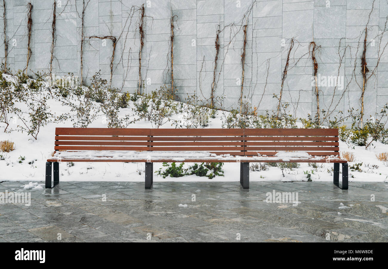 Panca in legno nella neve al parco durante l'inverno. Foto Stock