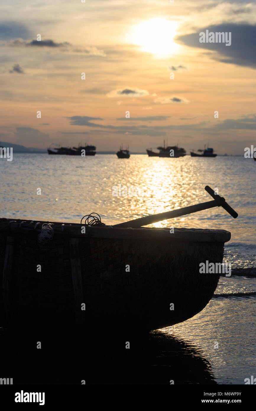 Il vietnamita barca da pesca di sagome in mare al tramonto Foto Stock