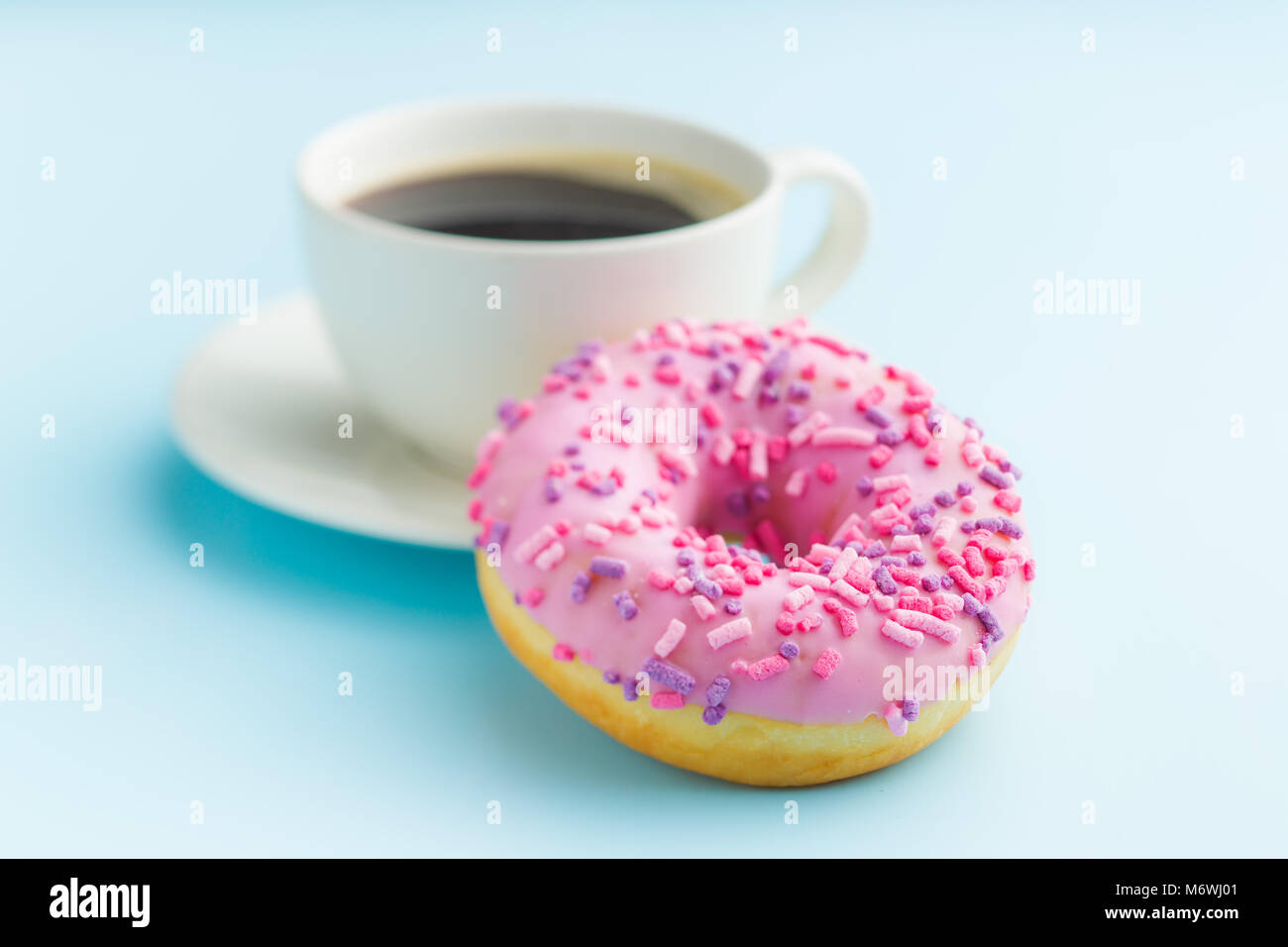 Ciambella di rosa e la tazza di caffè su sfondo blu. Foto Stock