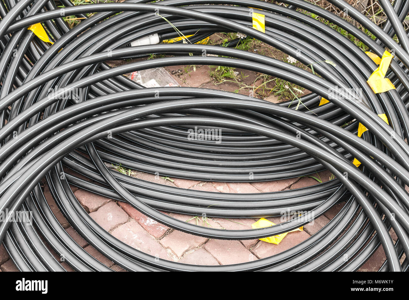 Arrotolare i cavi di plastica sdraiato sul pavimento di mattoni Foto Stock