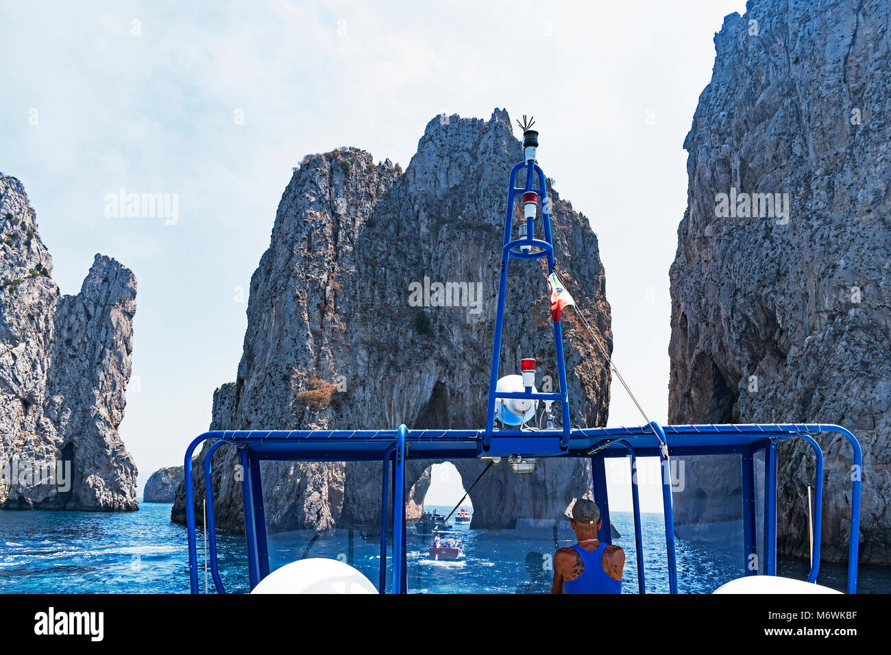 Imbarcazione turistica viaggio avvicinando i famosi faraglioni fuori dell'isola di capri nel golfo di Napoli. Foto Stock