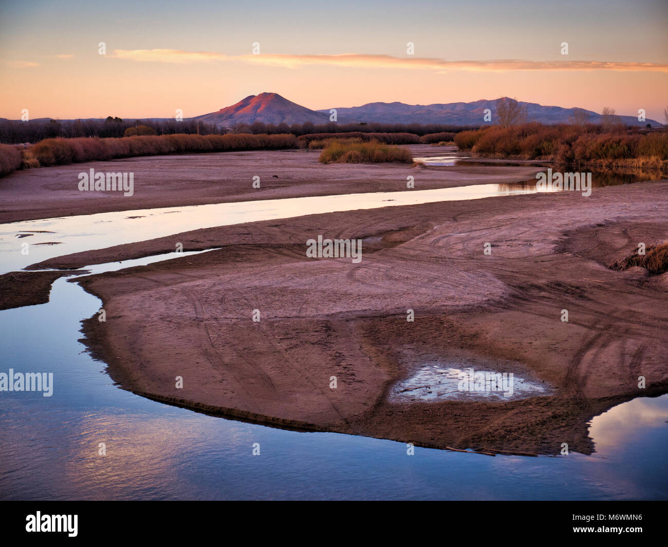 Rio Grande al solstizio d'inverno appena ad ovest di Mesilla, Nuovo Messico. L'acqua in questo importante fiume è ampiamente utilizzata per l'agricoltura. Picacho picco in bac Foto Stock