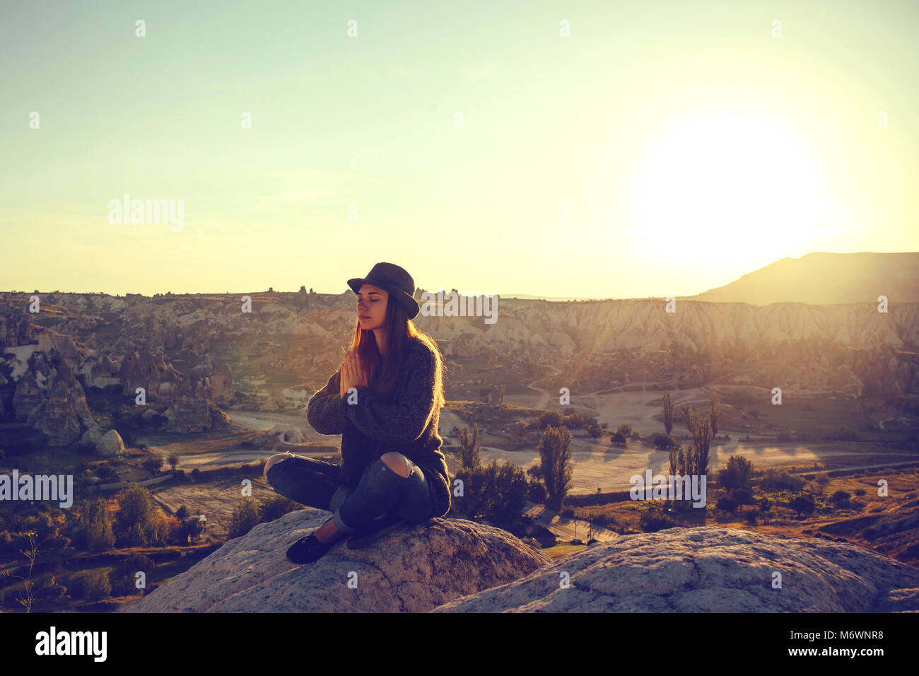 Giovane bella ragazza la pratica dello yoga sulla cima di una montagna in Cappadocia a sunrise. Pratiche di rilassamento. Foto Stock