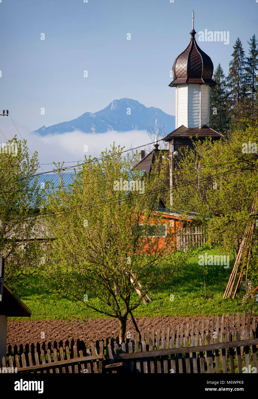 Bellissimo paesaggio a molla con chiesa e montagna. Petru Voda, Romania Foto Stock
