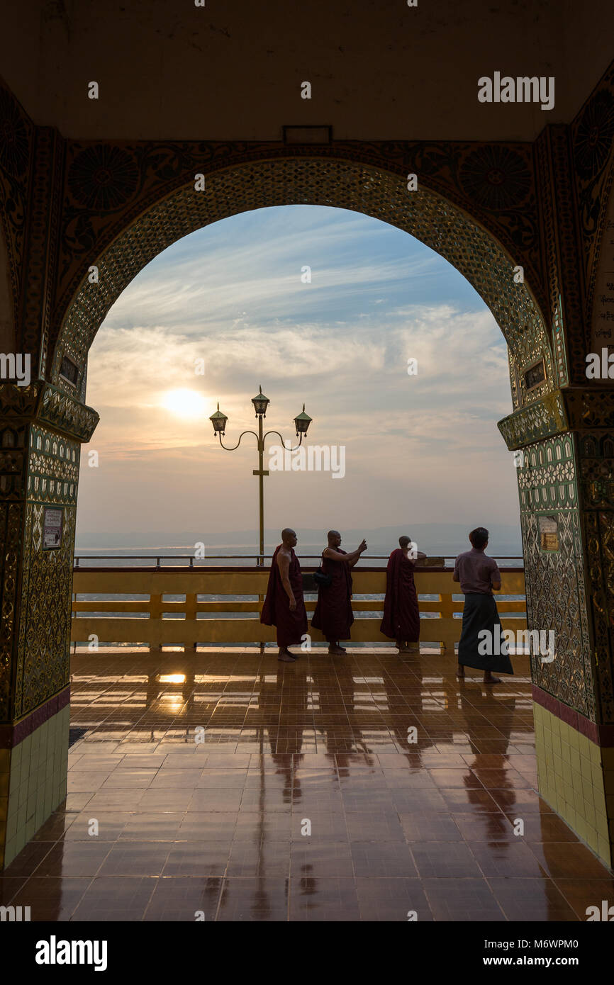 Tre monaci e un altro uomo gli ornati Sutaungpyei Pagoda al Mandalay Hill a Mandalay, Myanmar (Birmania) al tramonto. Foto Stock