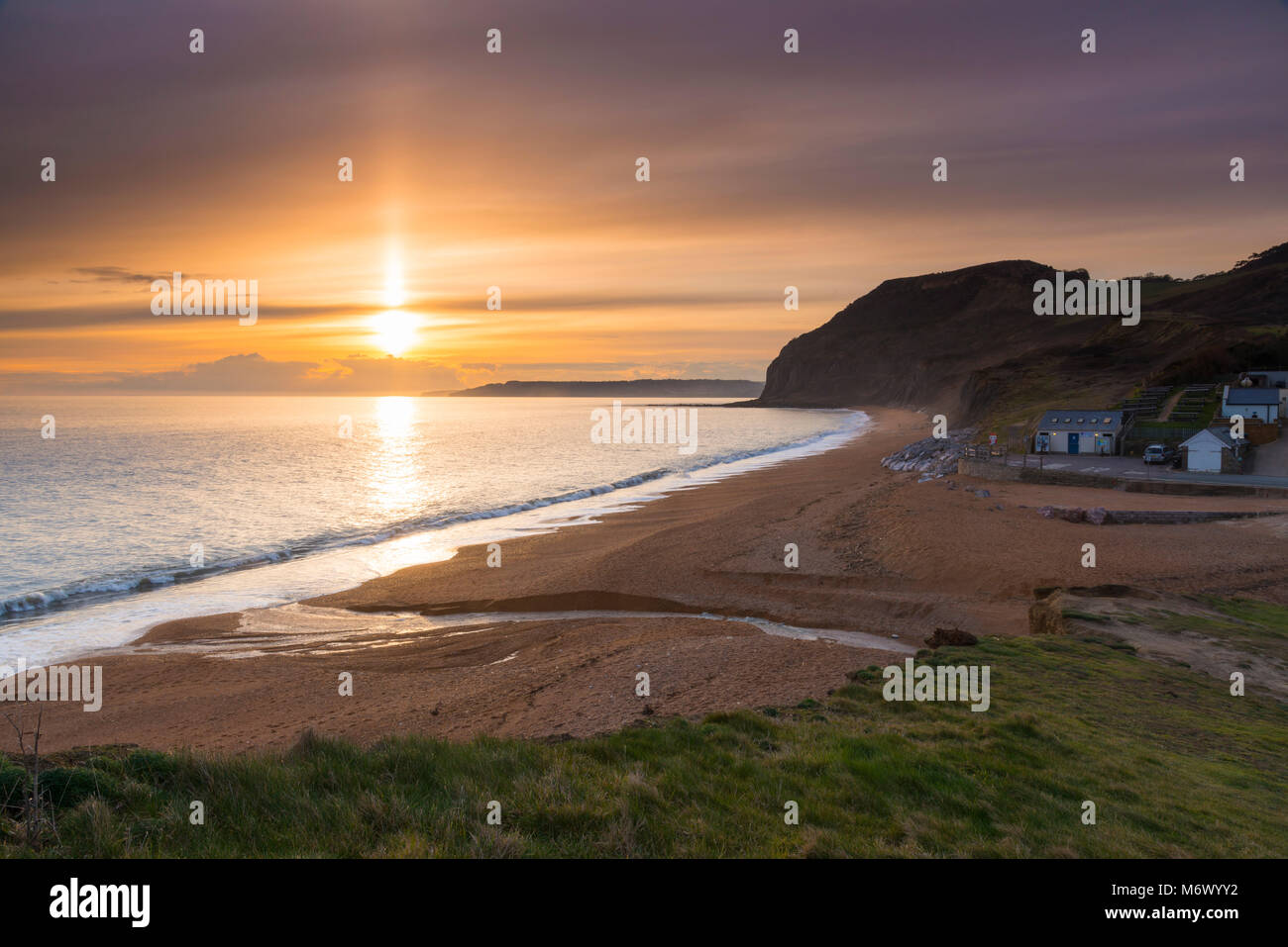 Seatown, Dorset, Regno Unito. Il 6 marzo 2018. Regno Unito Meteo. Un fascio di luce del sole splende alto sul livello alto nuvole che sono parzialmente oscurando il tramonto a Seatown su Jurassic Coast di Dorset. Credito Foto: Graham Hunt/Alamy Live News Foto Stock