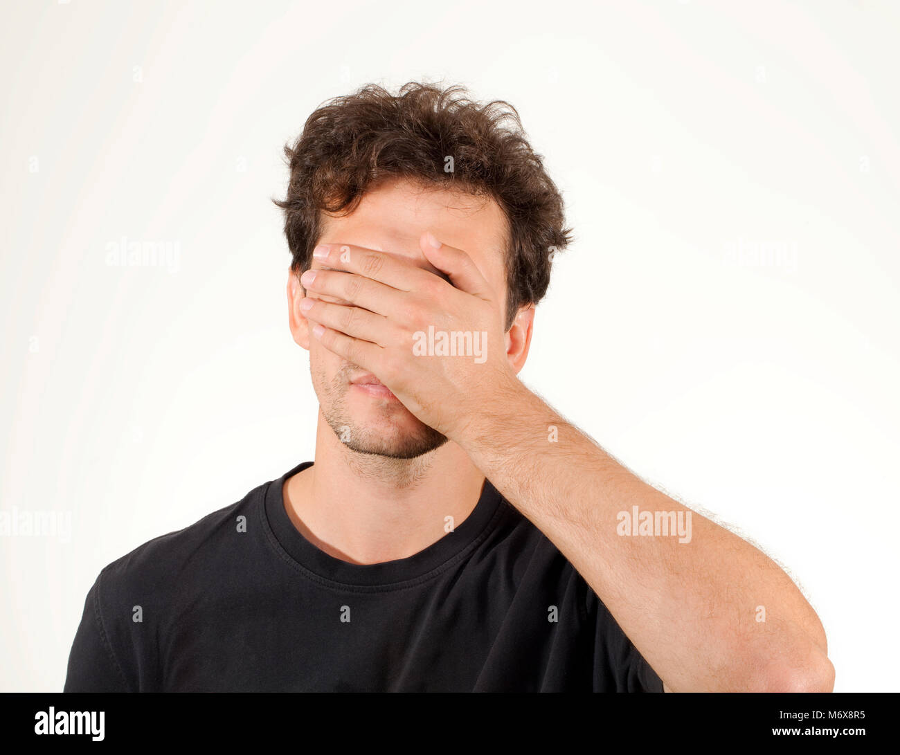 Uomo con capelli ricci chiudendo gli occhi con le mani Foto Stock
