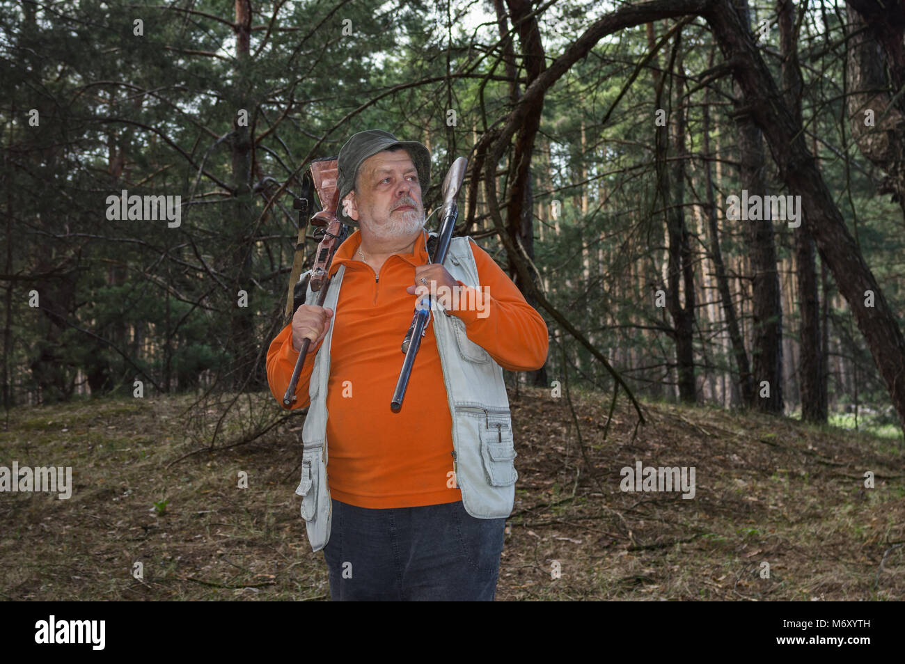 Ritratto di grave ranger senior con due fucili a canna rigata in piedi nel buio pineta Foto Stock