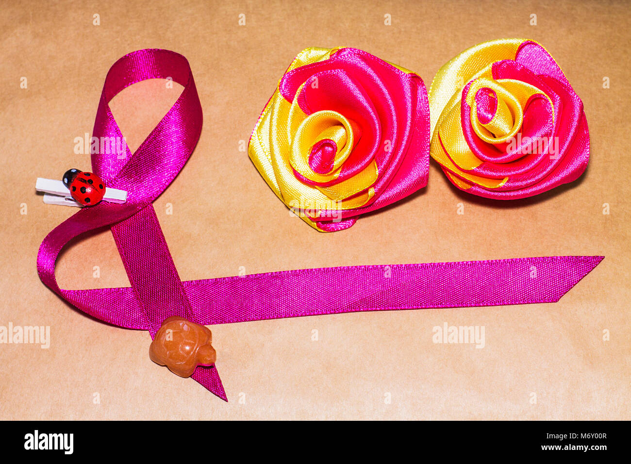 Il 8 marzo. Decorazione fatta di nastro decorativo con una coccinella e tartaruga e due fiori sullo sfondo marrone. Foto Stock