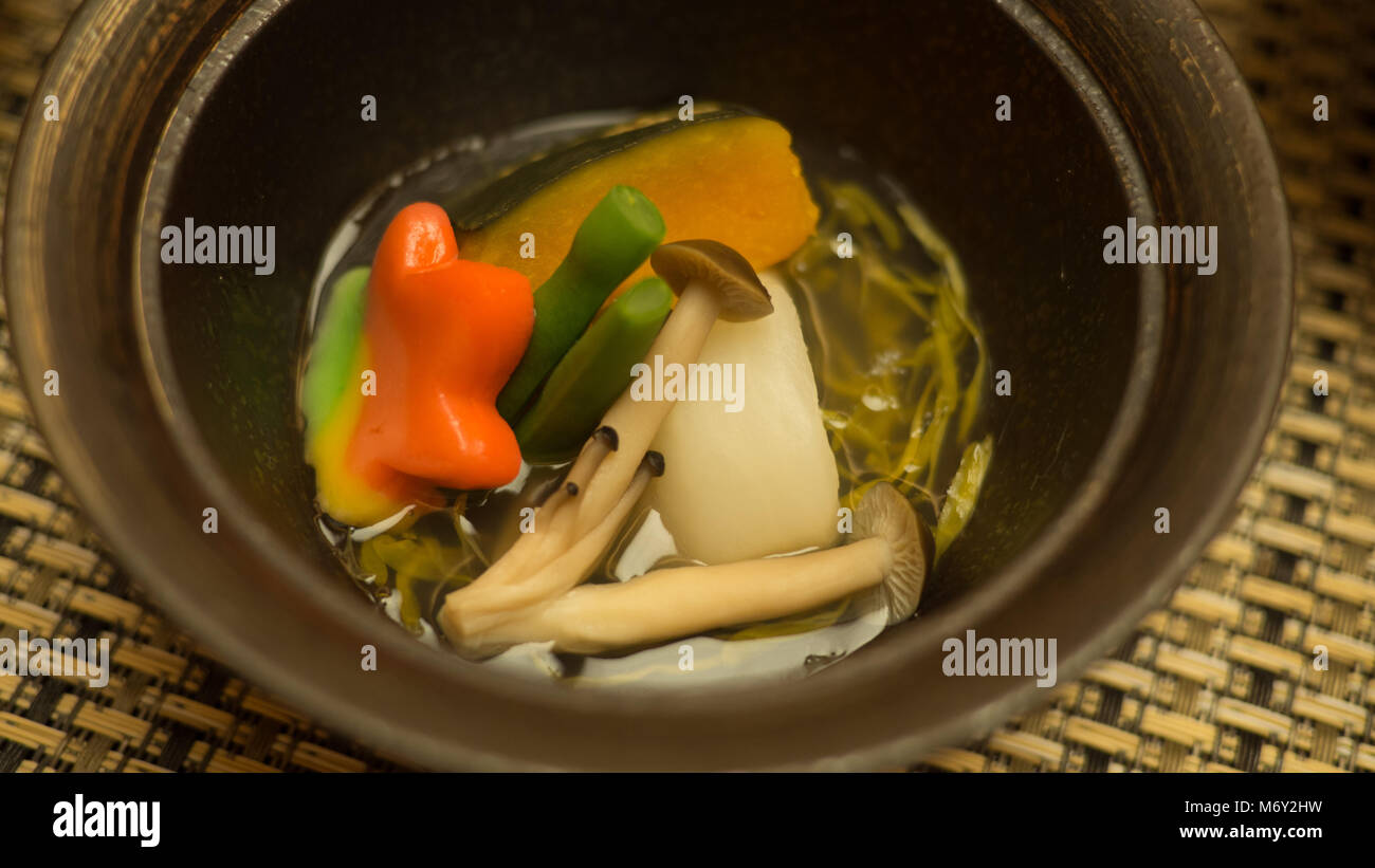 Un colorato zuppa che contiene un fungo, fagiolini, zucca e tofu serviti in una tradizionale cena giapponese conosciuta anche come Keiseki Foto Stock