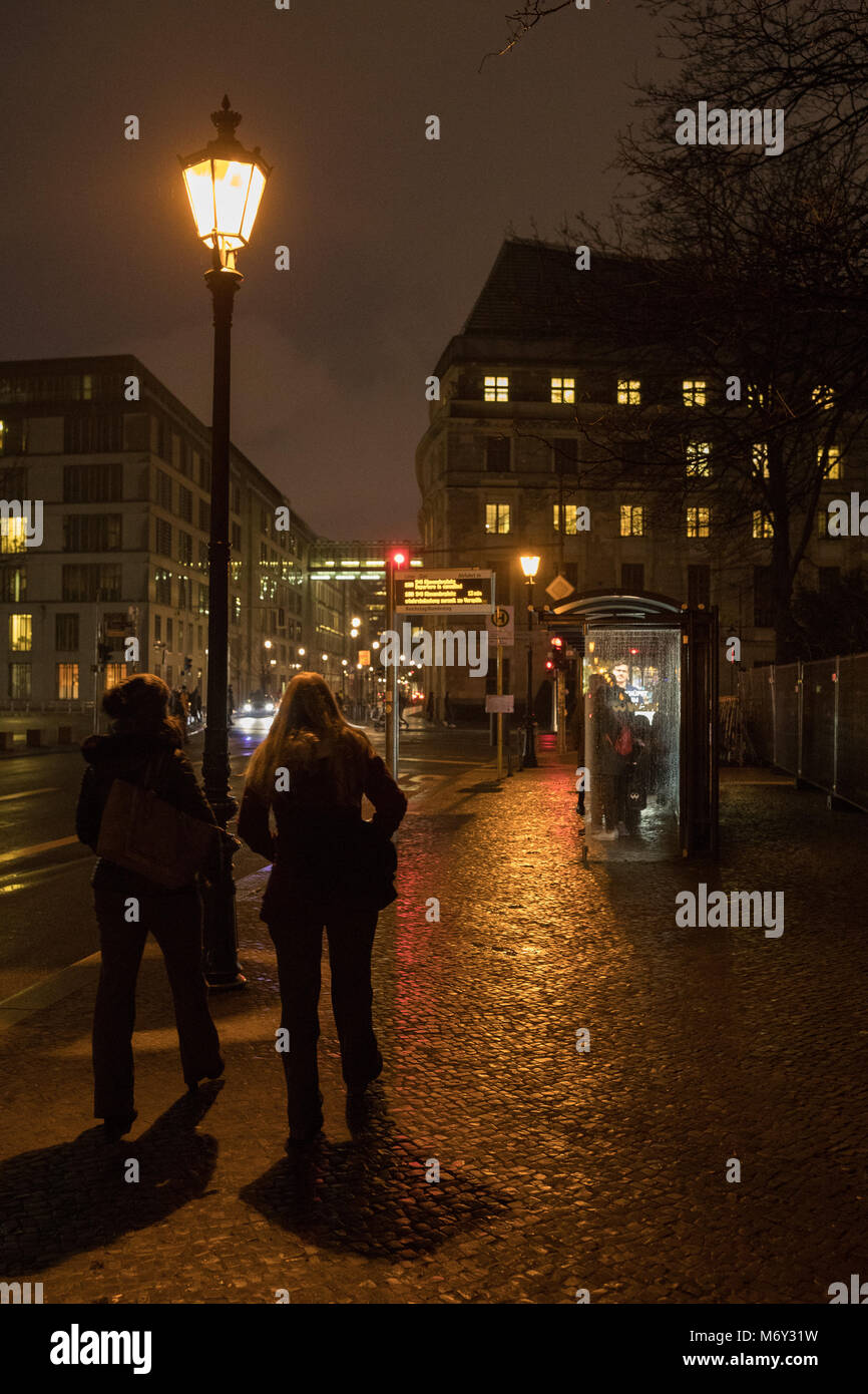 Due donne ad una fermata degli autobus in Scheidemannstrasse, nel quartiere Mitte di Berlino, Germania Foto Stock