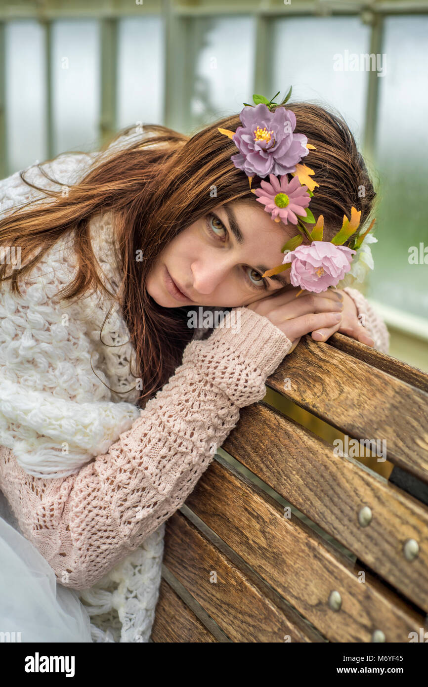 Donna che indossa un Fiore di Acconciatura di appoggio su di una panca in legno Foto Stock