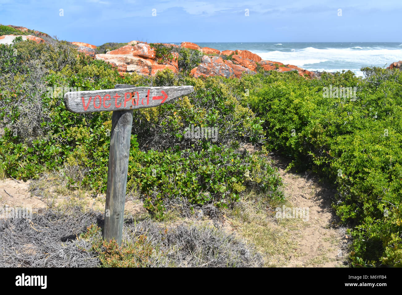Un sentiero in legno marcatura o segno vicino all'Oceano Indiano visto dalla Oyster Catcher sentiero vicino Mosselbay sulla Garden Route del Sud Africa popolare con Foto Stock