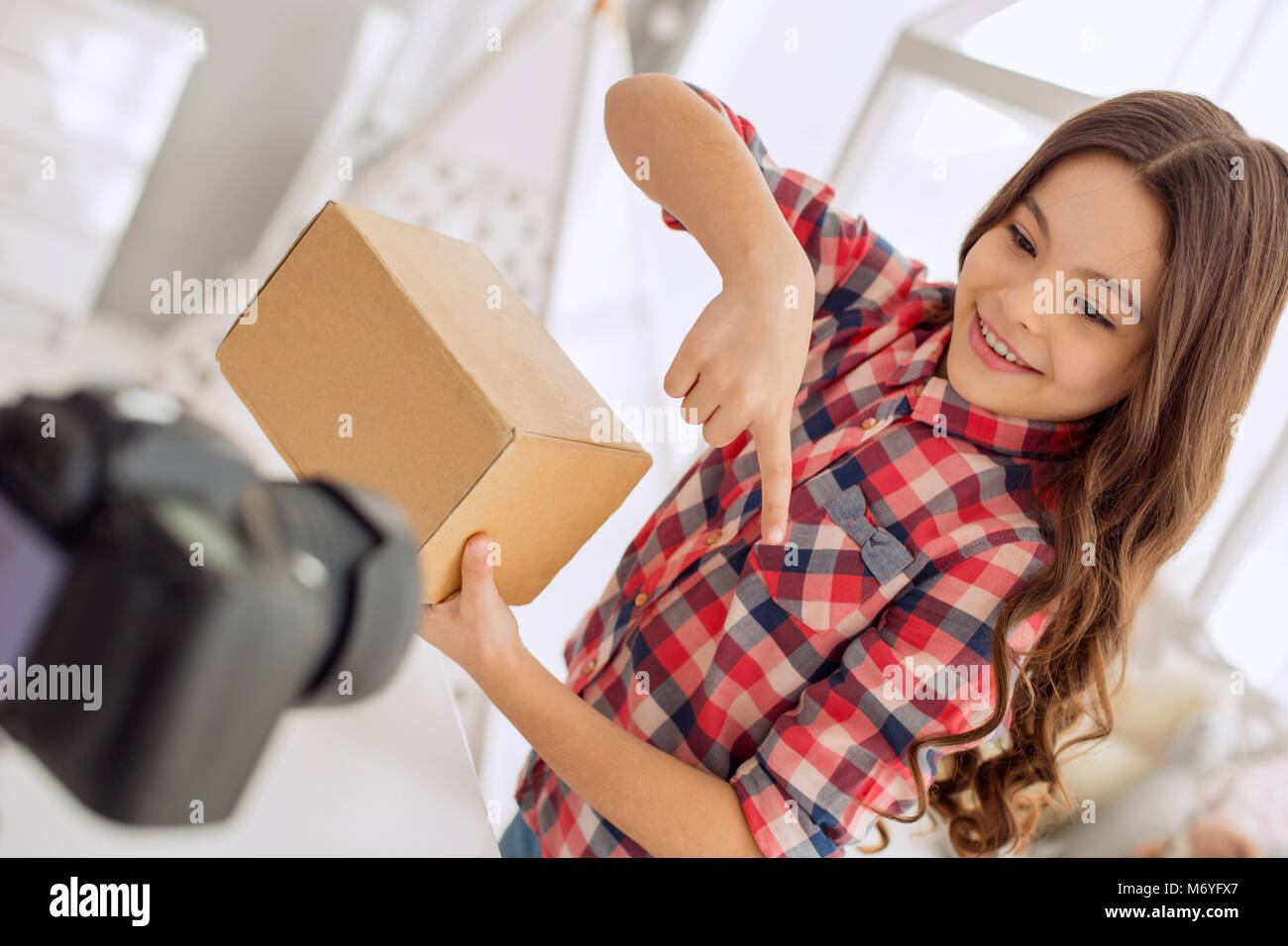 Ragazza gioiosa indovinando il contenuto della casella durante la registrazione vlog Foto Stock