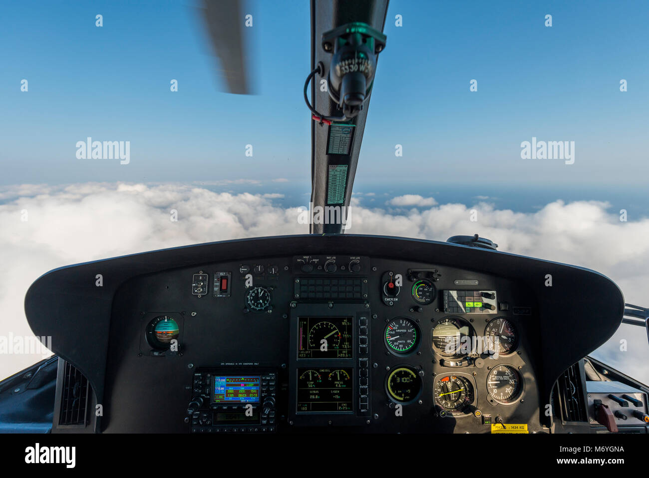 Cruscotto del pilota di elicottero visualizzare mentre si è in volo sopra le nuvole con una lama mobile e i controlli visibili Foto Stock